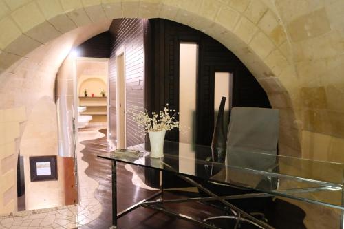 a glass table in a room with a stone wall at METEORON Luxury Rooms in Matera