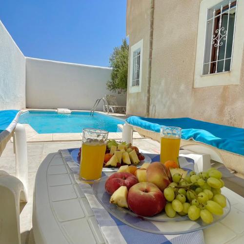 a plate of fruit on a table next to a pool at Villa Sunset résidence Djerba in Djerba