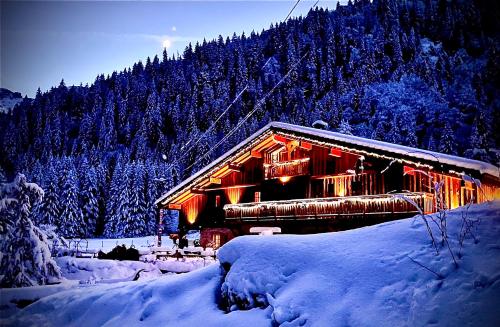 a cabin in the snow with lights on at Aux lits du bronze Le mole in Mont-Saxonnex