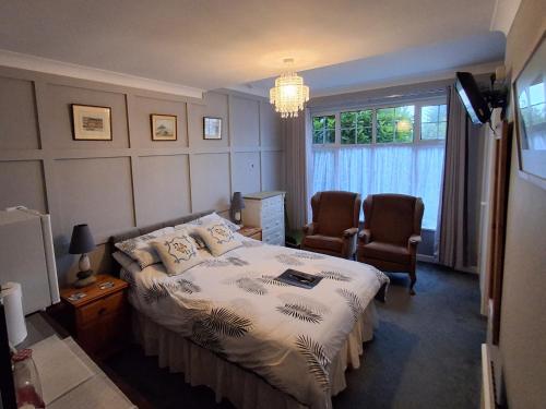a bedroom with a bed and two chairs and a window at Newton House in Torquay