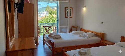two beds in a room with a balcony at Elena Rooms in Agios Nikitas