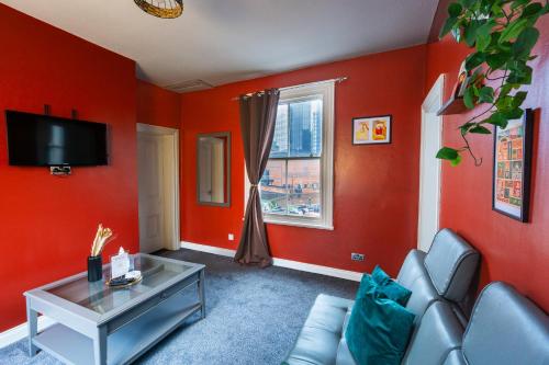 a living room with red walls and a couch and a window at Cozy flat by Birmingham Canals & City Centre in Birmingham