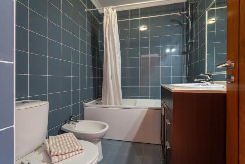 a blue tiled bathroom with a toilet and a sink at Santa Maria Apartamentos in Tavira