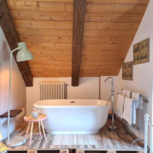 a large white bath tub in a bathroom with wooden ceilings at Locanda del Sasso Rooms in Crodo