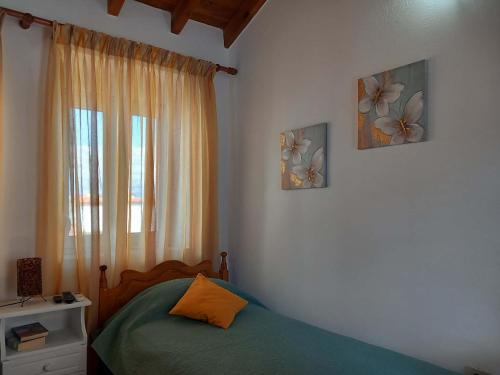 a bedroom with a bed with two pictures on the wall at Giannis' House in Polichnítos