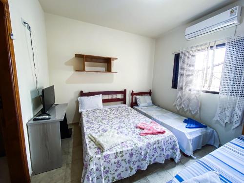 a bedroom with two beds and a television in it at Recanto the beach pousada in Iguape