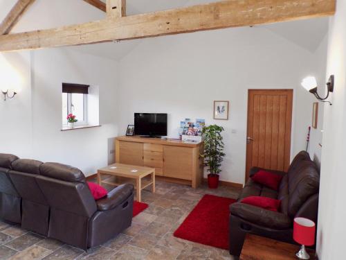 a living room with two leather chairs and a television at The Byre in Great Ayton