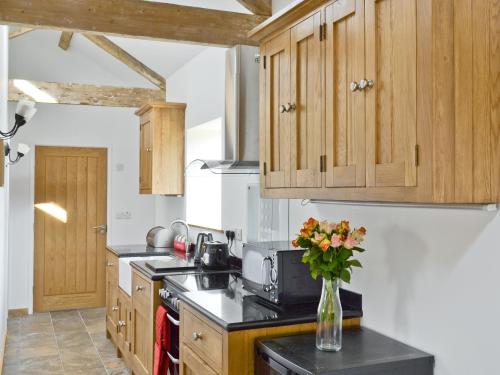 a kitchen with wooden cabinets and a vase of flowers on the counter at The Byre in Great Ayton