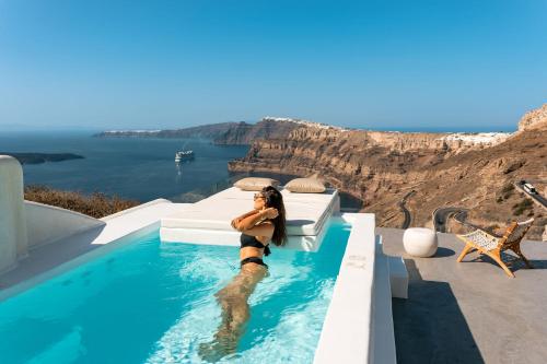 a woman in a swimming pool with a view of the ocean at Nelya Suites in Megalochori
