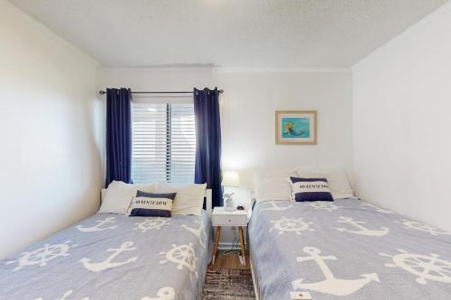a bedroom with two beds and a window with blue curtains at ABPAB166 Sandy Shores in Atlantic Beach