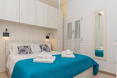 a white bedroom with two towels on a bed at Cala Lupo Relax Veranda e BBQ nel verde in Stintino