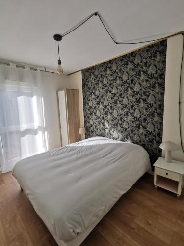 a white bed in a bedroom with a wall at La coccinelle in Gujan-Mestras
