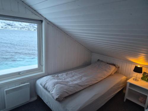 a small bed in a room with a window at Arctic Sea house in Svensby