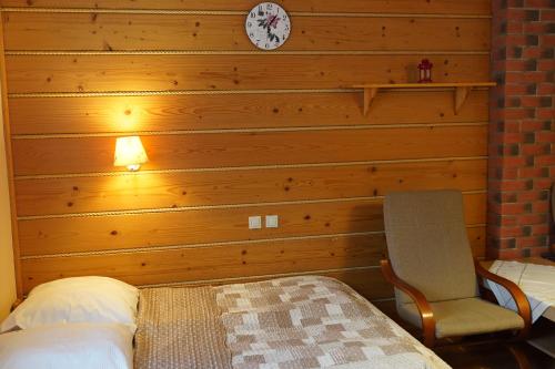 a bedroom with a wooden wall with a bed and a chair at Willa Wisełka in Wisła