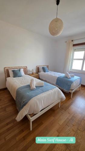 a bedroom with two beds and a pendant light at Maia Surf House - Baleal in Ferrel