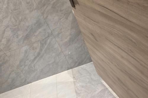 a bathroom with a marble tile floor and a wooden wall at Ijumba Signature Hotel in Bellville