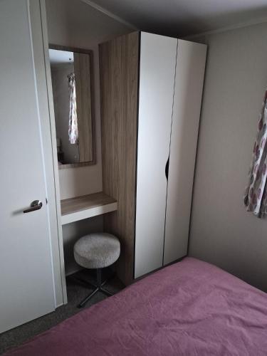 a bedroom with a bed and a mirror and a closet at Poppy Caravan in Leysdown-on-Sea