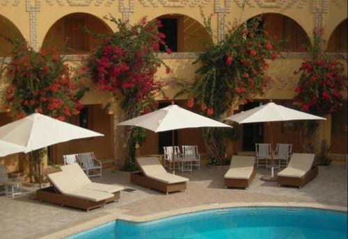 a patio with chairs and umbrellas next to a pool at Ksar El Jerid in Tozeur