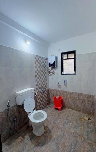 a bathroom with a toilet and a red stool at Yatri Lakeview Villa in Pune
