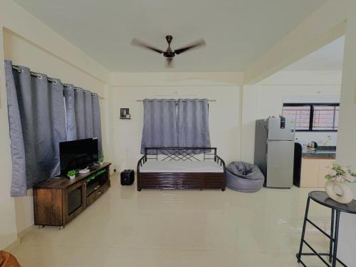 a living room with a bed and a tv and a refrigerator at Yatri Lakeview Villa in Pune