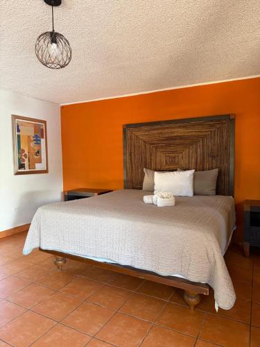 a bedroom with a large bed with an orange wall at Hacienda Rosarito in Rosarito Beach