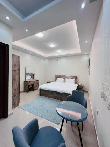 a bedroom with a bed and two blue chairs at Quba Suites نزل قباء in Medina