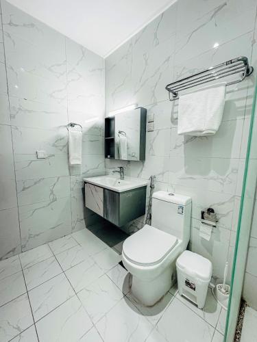 a white bathroom with a toilet and a sink at Quba Suites نزل قباء in Medina