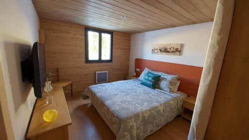 a small bedroom with a bed and a television at Le Chalet in Selonnet