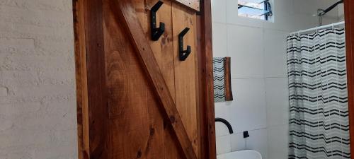 eine Holztür in einem Badezimmer mit Toilette in der Unterkunft CabañaPaz in Santa Rosa de Calamuchita