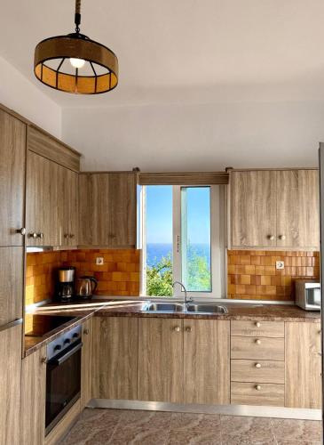 a kitchen with wooden cabinets and a large window at Ftero Traditional Retreat in Manganítis