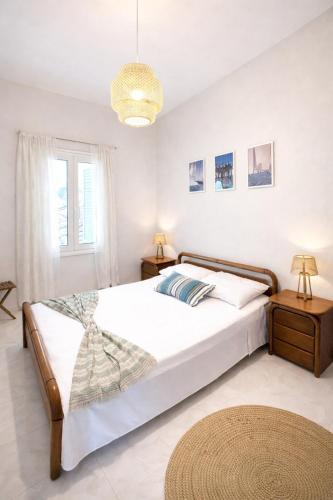 a white bedroom with a bed and a window at Ftero Traditional Retreat in Manganítis