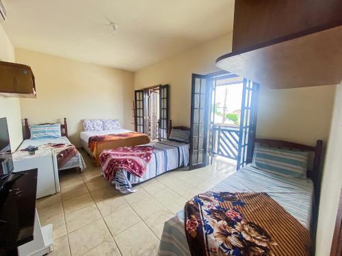 a room with three beds and a tv in it at Recanto the beach pousada in Iguape