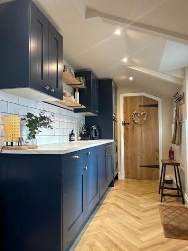 a kitchen with blue cabinets and a wooden floor at The Snug, Minehead in Minehead