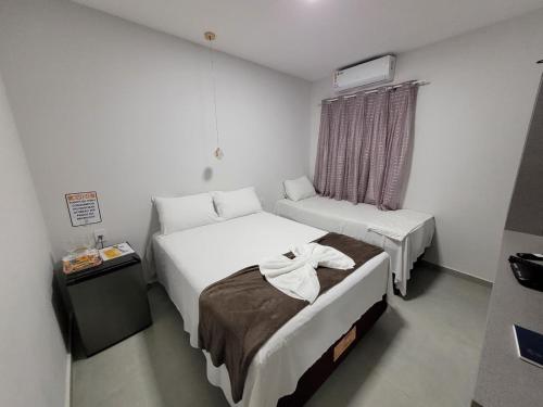 a hotel room with two beds and a window at Pousada Novo Millenium in Araripina