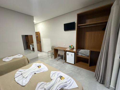 a hotel room with two beds and a desk at Hotel Castelo do Lago in Fama