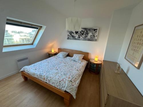 a bedroom with a bed with two lamps on it at Jolie maison de vacances in Concarneau
