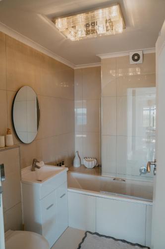 a bathroom with a tub and a sink and a mirror at Seaside tranquility in Gonubie in East London