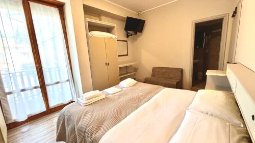 ein Schlafzimmer mit einem Bett, einem Stuhl und einem Fenster in der Unterkunft Umbria Green Central Rooms in Castiglione del Lago