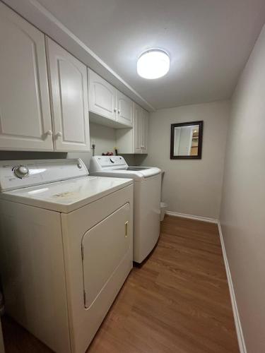 a laundry room with white cabinets and a washer and dryer at 2 Bedroom 1 Bathroom Basement Suite in Toronto