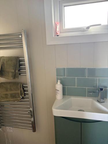 a bathroom with a sink and a window and towels at Whitethorn Shepherds Hut in Bellaghy