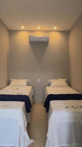 a room with two beds with white sheets and a heater at Villa Safira Residence in Caxias das Aldeias Altas