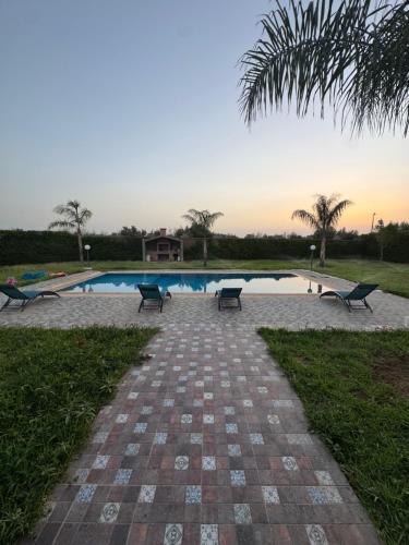 a swimming pool with benches in front of a resort at villa lina in Aït Mazou