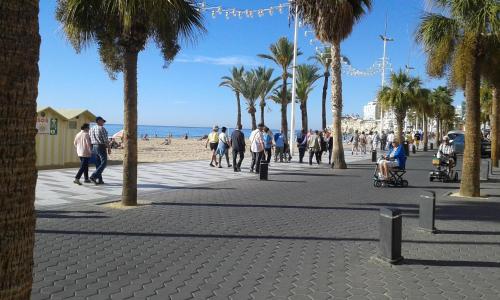 a group of people walking on a sidewalk near the beach at Apartamento REX in Benidorm