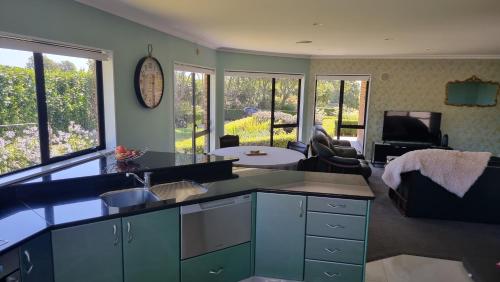 a kitchen with blue cabinets and a living room at Rosandra Retreat 2 in New Plymouth
