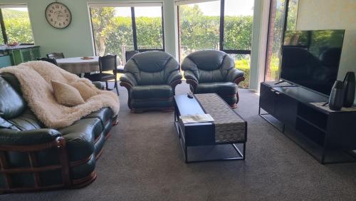 a living room with couches and a flat screen tv at Rosandra Retreat 2 in New Plymouth