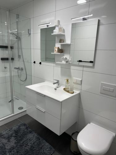 a white bathroom with a sink and a shower at City-Apartment Braunschweig in Braunschweig