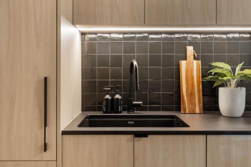 a kitchen with a sink and a black tiled wall at Smithe House in Vancouver