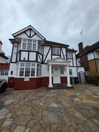 a large white and black house with a driveway at 10 Minutes to Wembley Stadium Guest Rooms in London