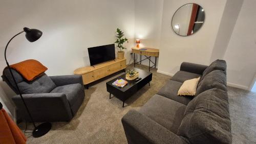a living room with a couch and a chair and a tv at Sleek 1 Bed Flat near Warwick Castle with Parking in Warwick