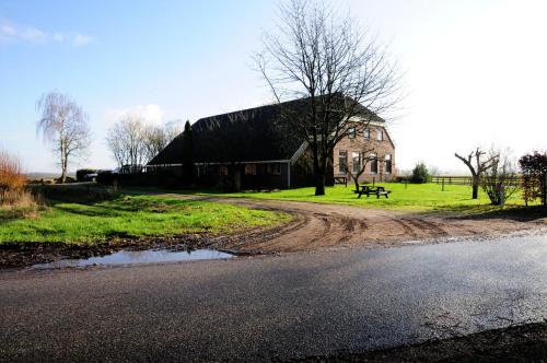 a barn with a puddle of water next to a road at Vledderstee in Vledderveen